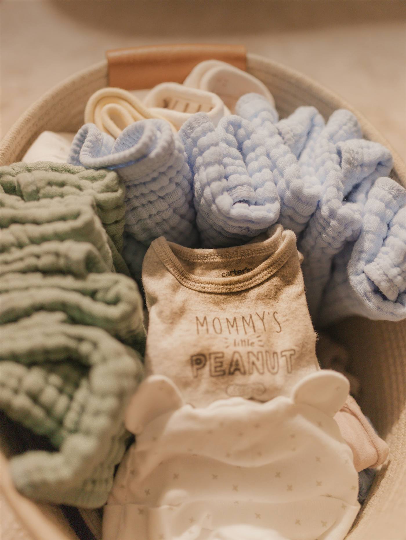 Woven basket of folded baby clothes and essentials for Canadian parents