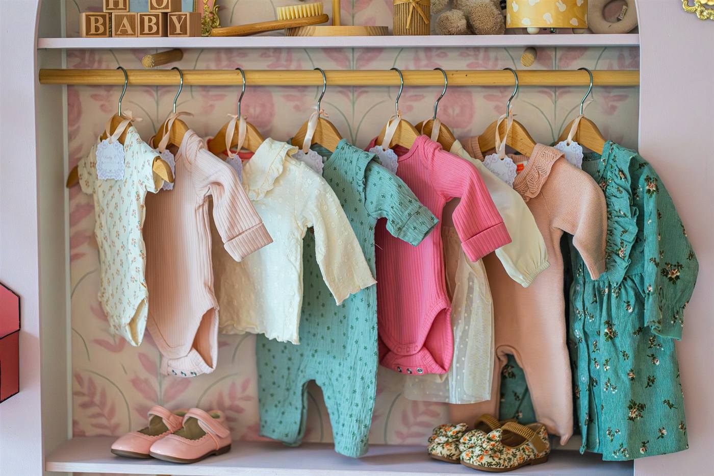 Rack of secondhand baby and kids' clothing with shoes below, at a Canadian resale shop